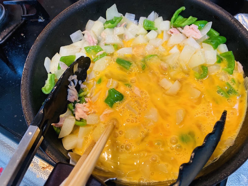 フライパンで野菜と溶き卵を火にかける