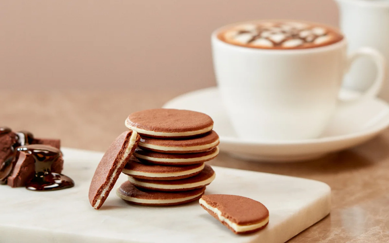 コーヒーチーズチョコクッキーサンドとラテの写真
