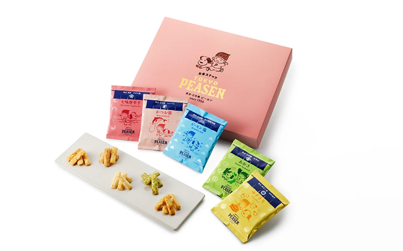 ピンクの箱とカラフルな小袋、皿にのったせんべいの写真