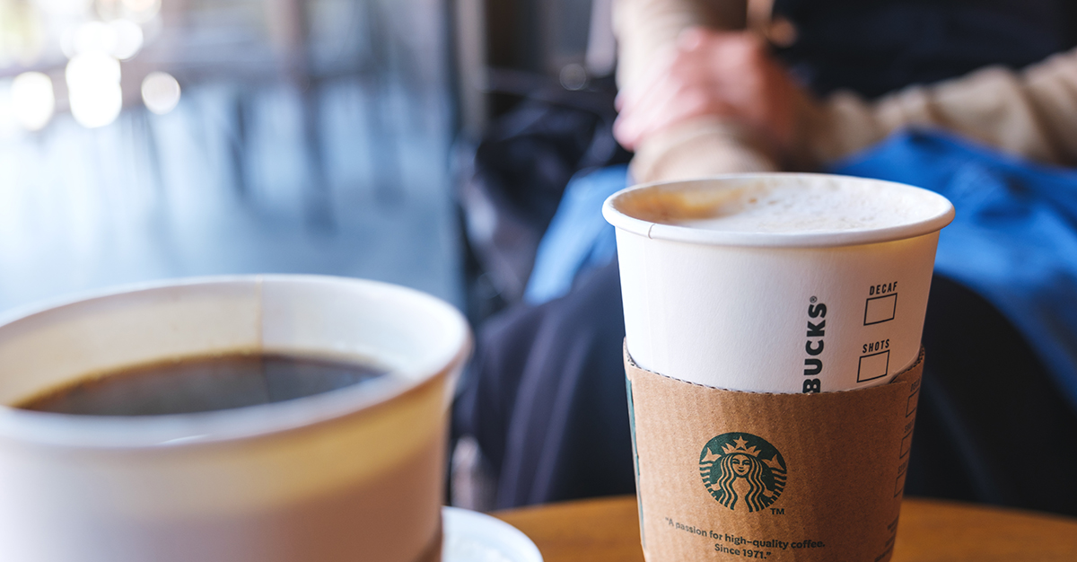 カフェのテーブルにコーヒーの入った紙コップが並んでいる様子