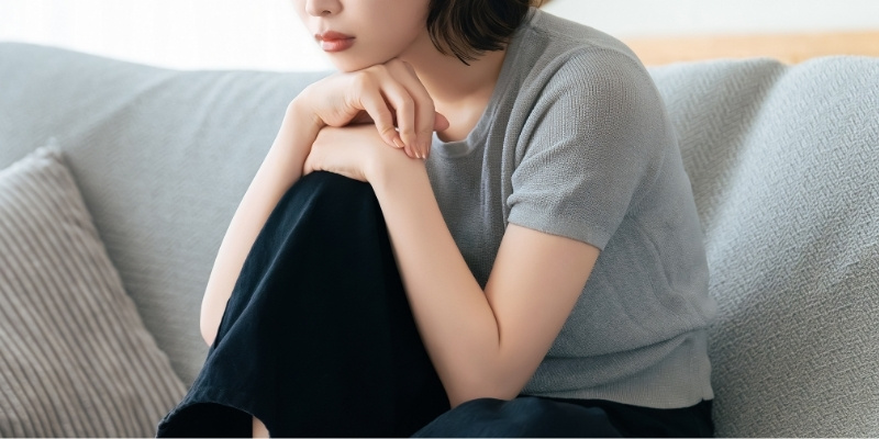 暗い表情でソファに座っている女性の写真