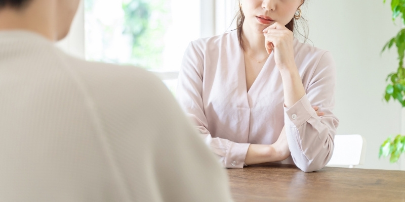 鋭い顔で男性と話している女性の写真
