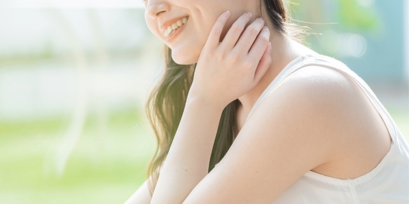 明るい緑の中でほほ笑む女性の写真