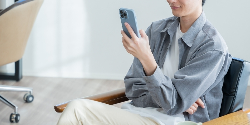 スマホを見てほほ笑む男性の写真