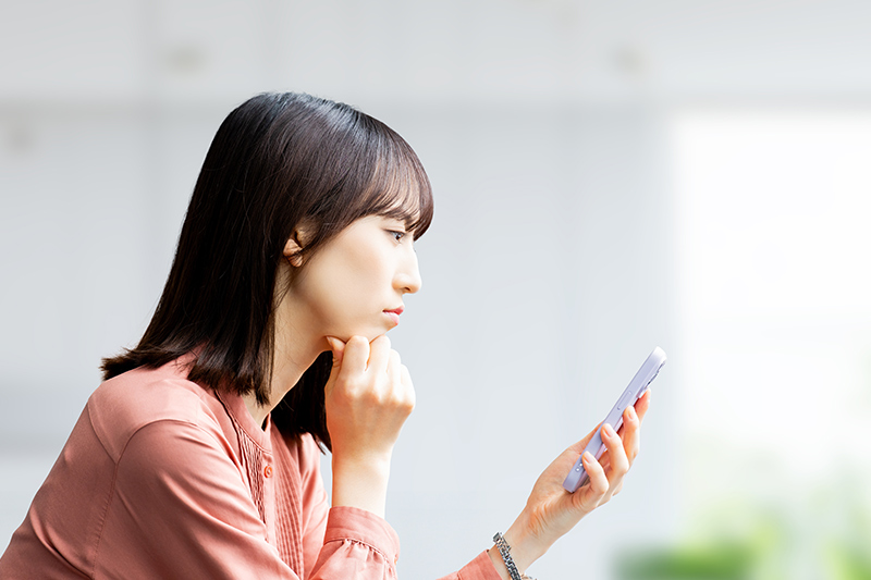 スマホを見て考える女性