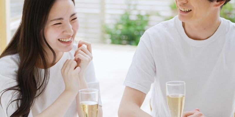 お酒を飲みながらほほ笑む女性と男性の写真