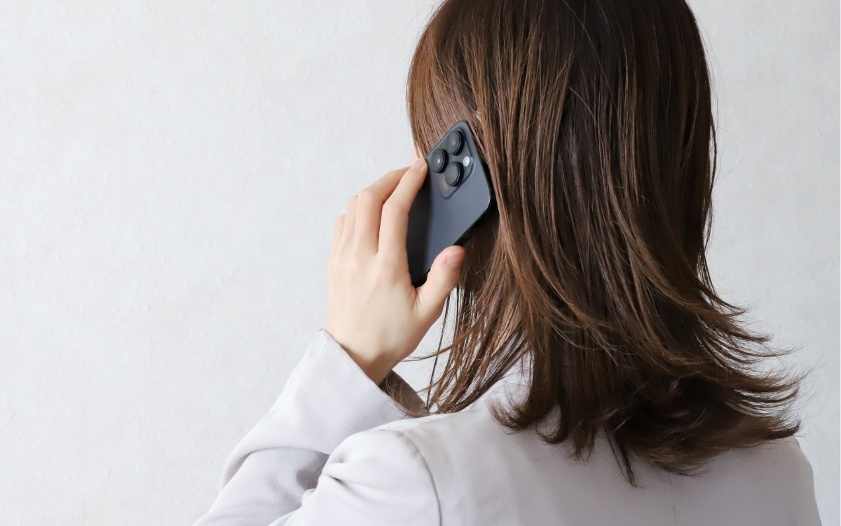 スマホで通話する女性の後姿の写真