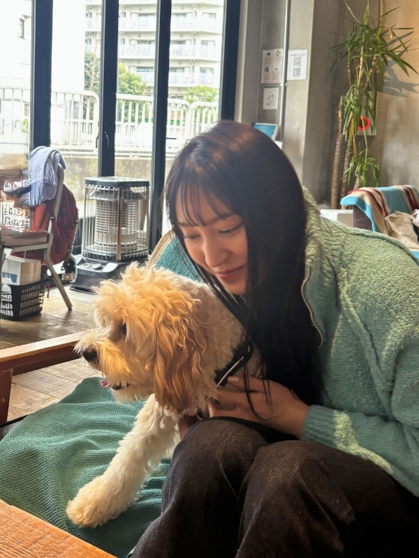カメラと別の方向を向く愛犬を抱くAKIKAさんの写真