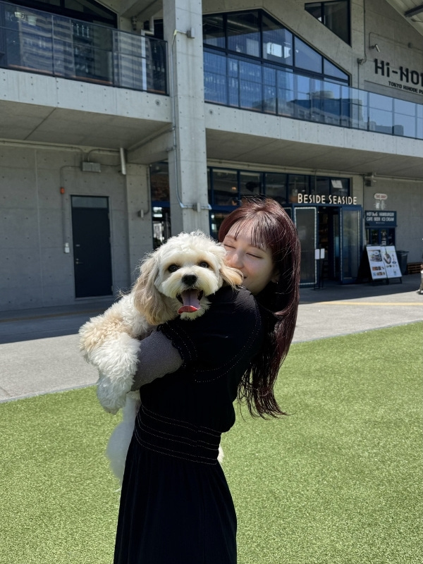 カメラ目線の愛犬と目を閉じて抱きしめるAKIKAさんの写真