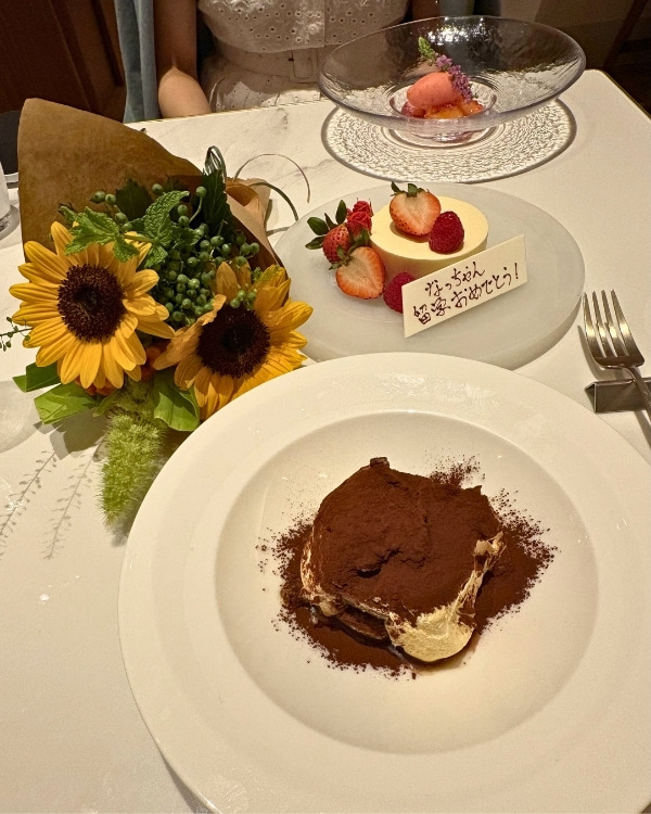 ヒマワリの花束と留学おめでとうと書かれたプレートスイーツの写真