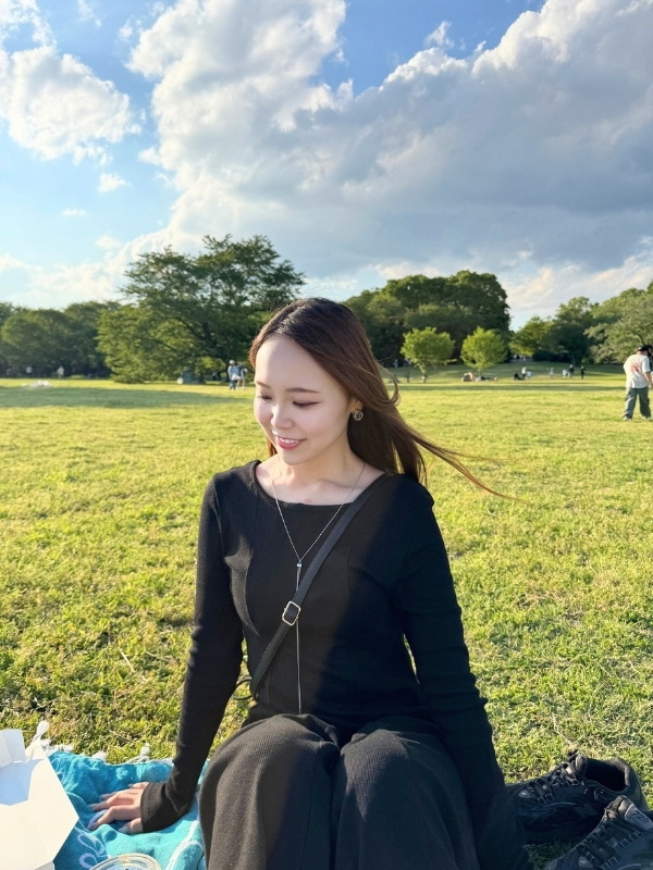芝生の上にレジャーシートをしいて座る松山さんの写真