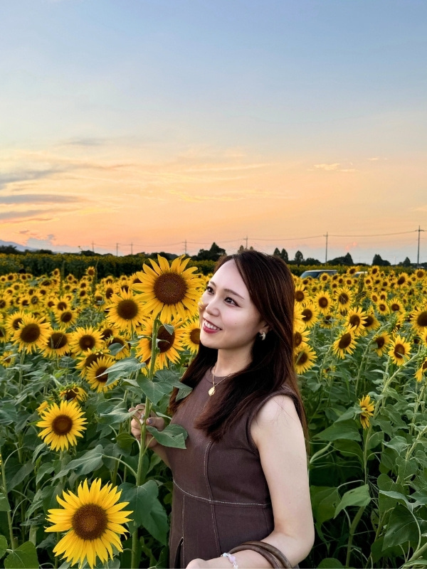 ヒマワリに顔を寄せる松山さんの写真