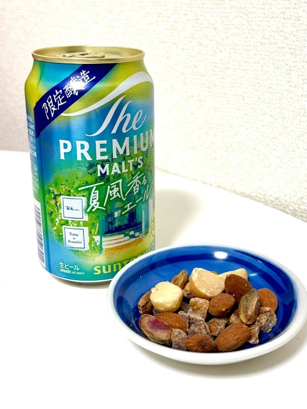 缶ビールと夜に食べたいナッツをお皿に乗せている写真