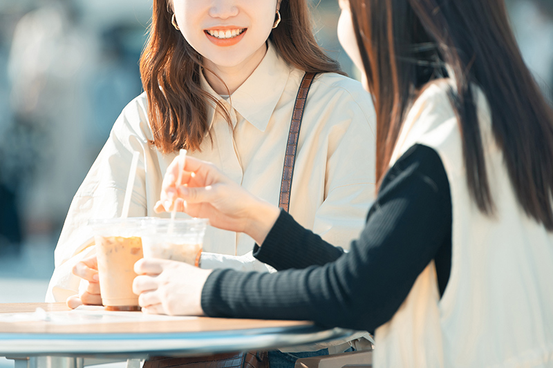 テラス席でコーヒーを飲む2人の女性