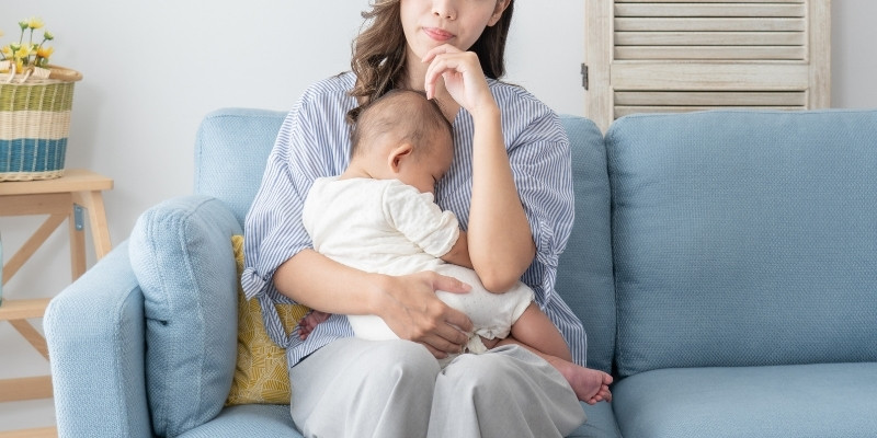 子供を抱いて考える女性の写真