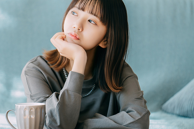 肘をついて考えごとをする女性