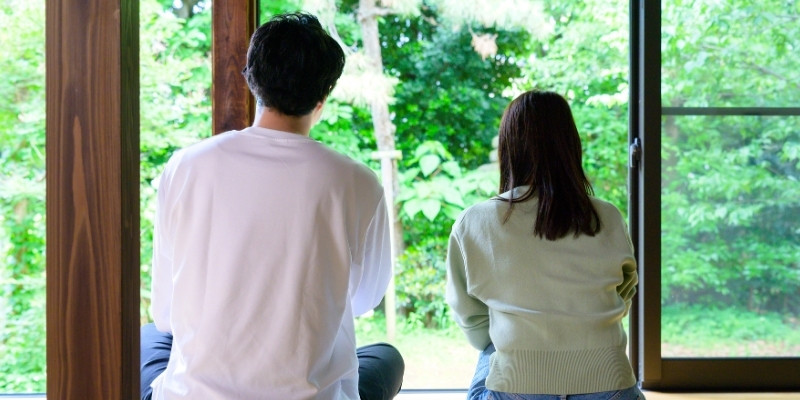 縁側に並んで座る男女の後ろ姿の写真