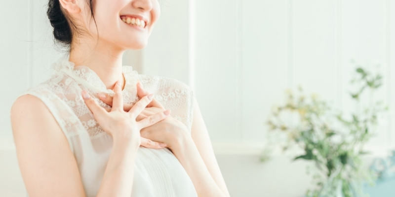 両手を胸に当ててほほ笑む女性の写真