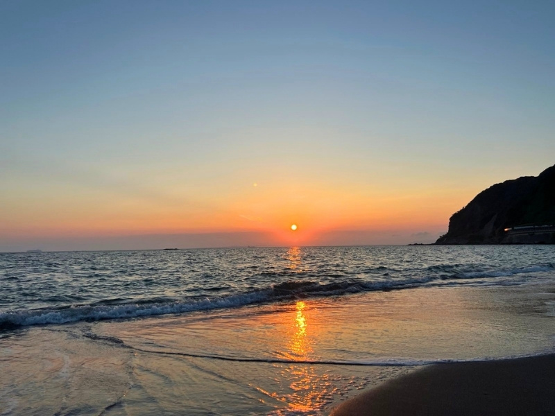 水平線に夕日が落ちていく写真