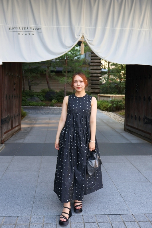 ホテル入り口で撮影した黒ワンピースの松山さんの写真