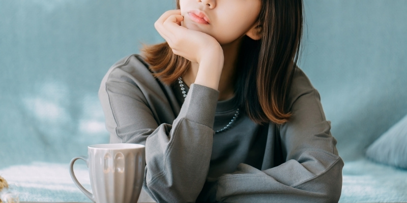 頬杖をつくアンニュイな表情の女性の写真