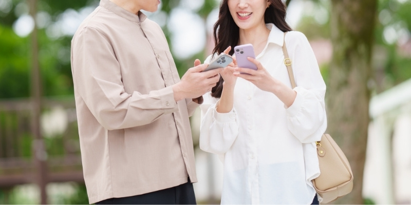 スマホを見せ合っているカップルの写真