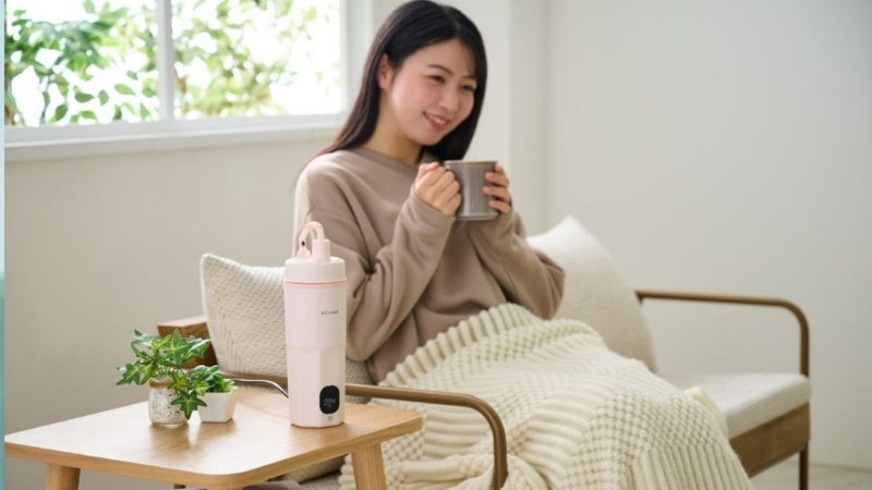 ケトルの隣で白湯を飲んでいる女性の写真