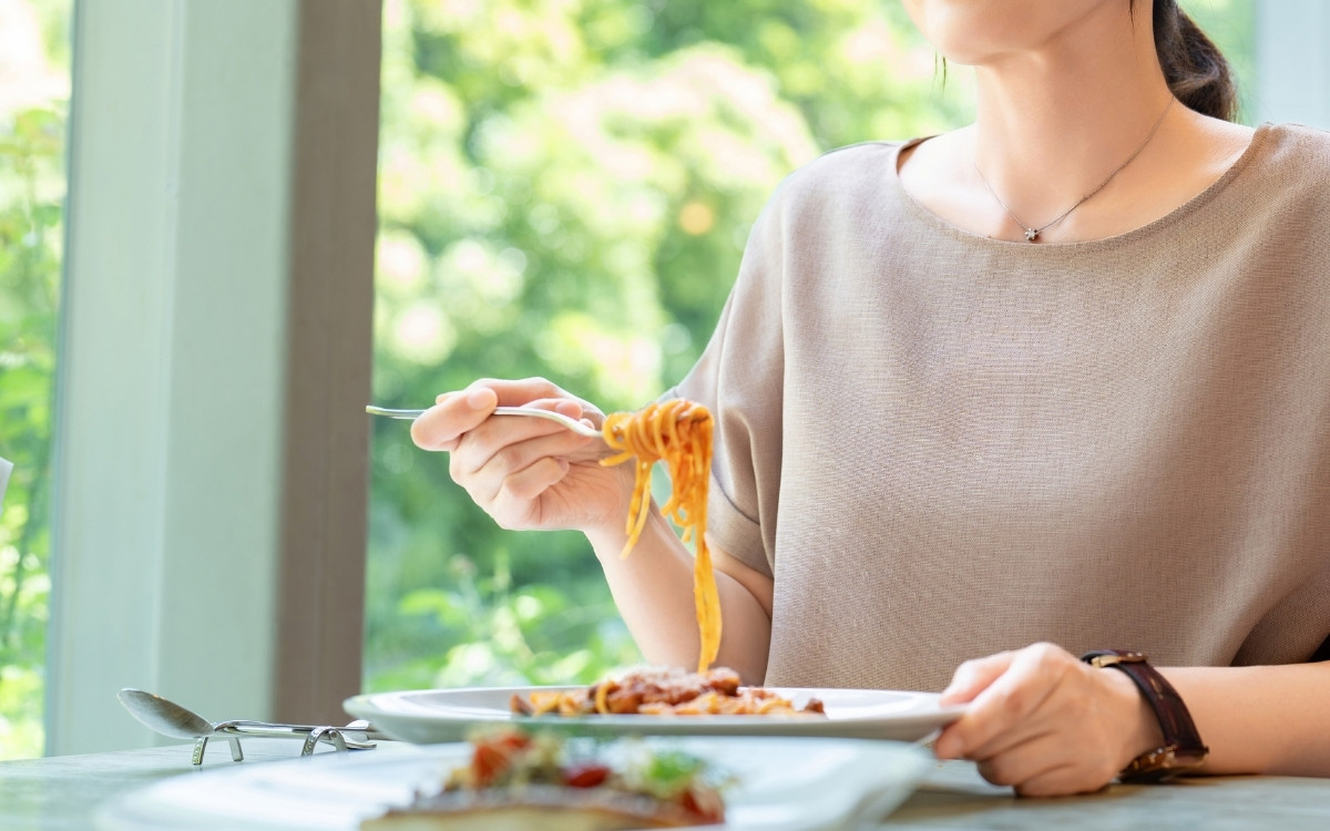 お店でパスタを食べている女性の写真