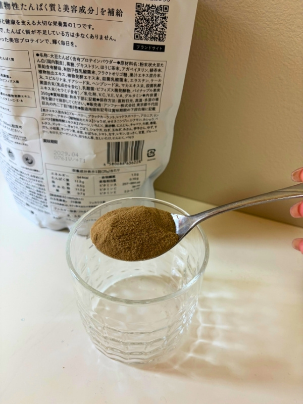 スプーンに持ったプロテインをガラスカップに入れている写真