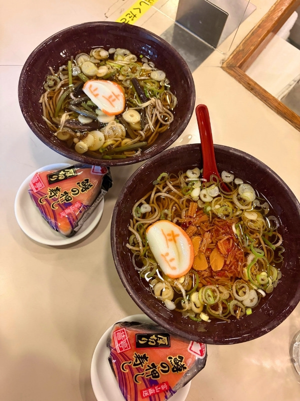山菜と立山と書かれたかまぼこのそば、おにぎり型の鱒のすしの写真
