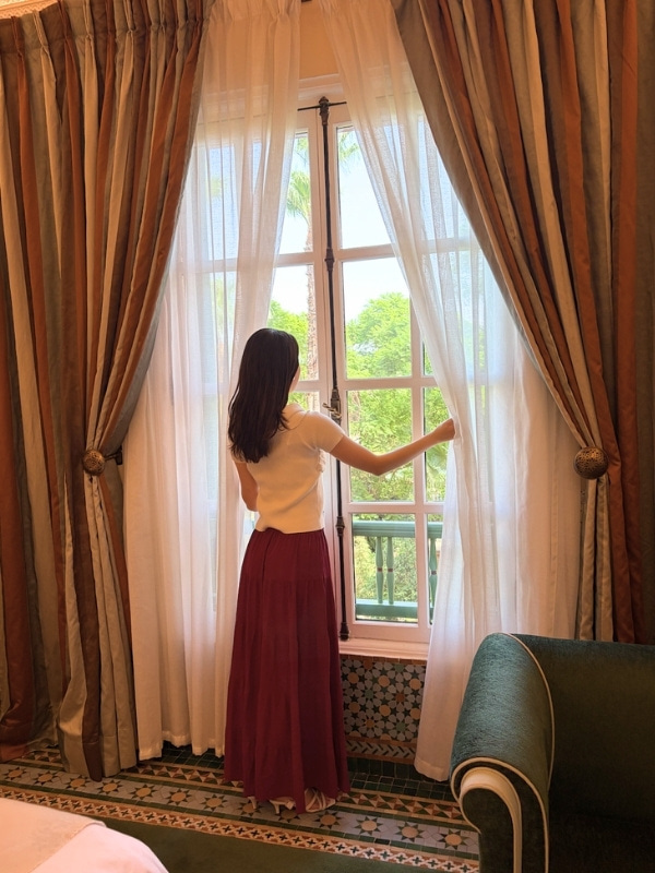 客室のカーテンを開く上西さんの後姿の写真